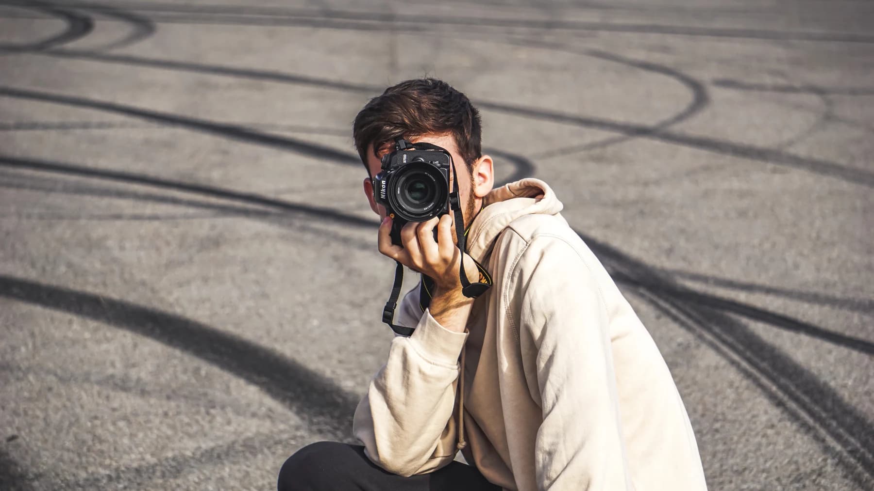 Fotograf mit Kamera auf einer Asphaltfläche