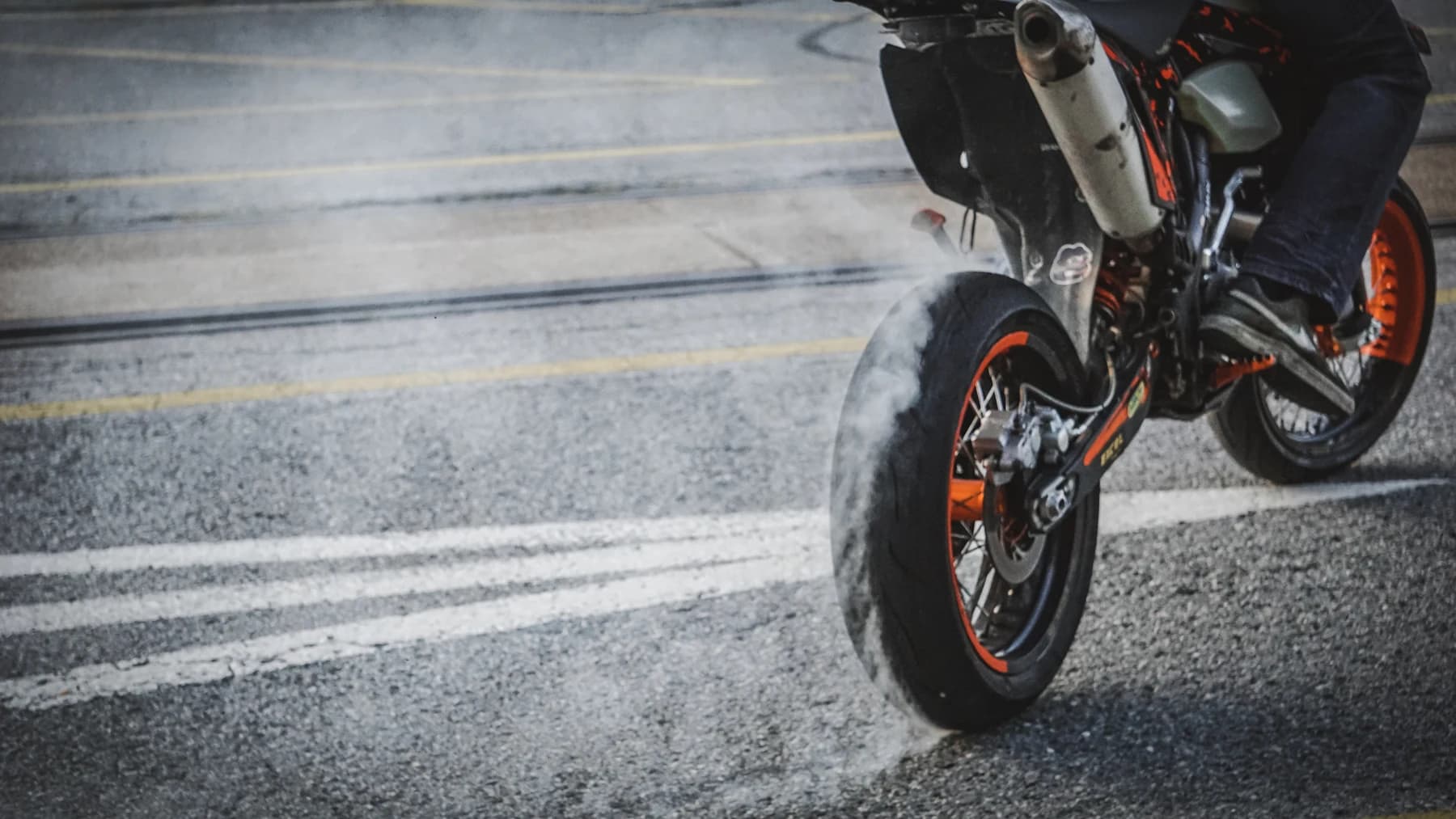 Detail eines Motorrads mit angehobenem Vorderrad auf Asphalt