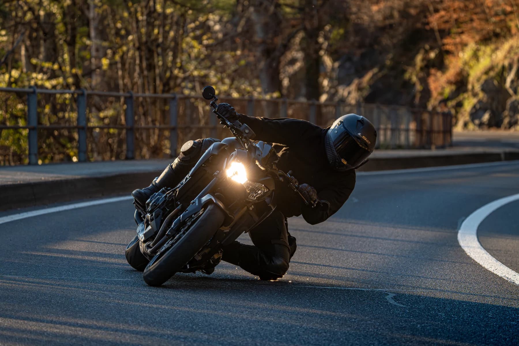Motorradfahrer in Schräglage auf einer Strasse im warmen Sonnenlicht