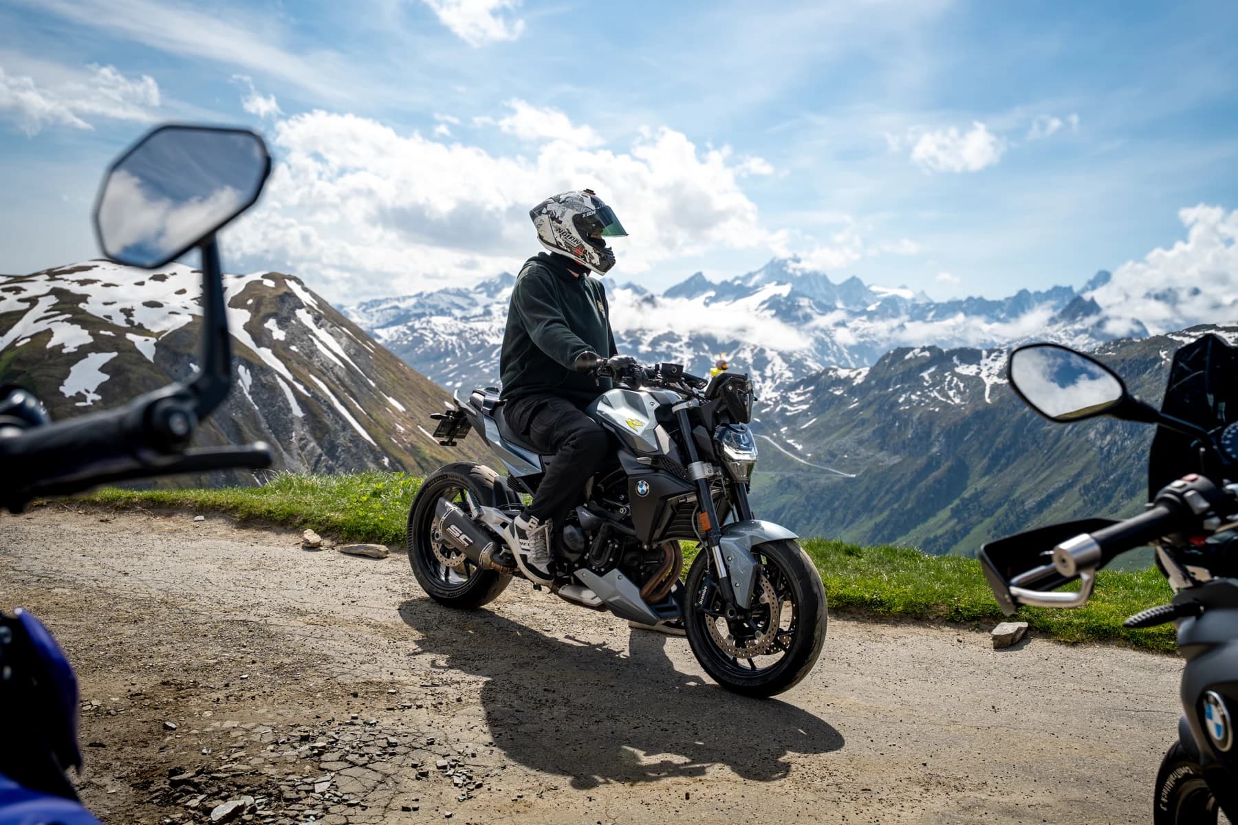 Motorradfahrer vor dem Panorama schneebedeckter Alpen