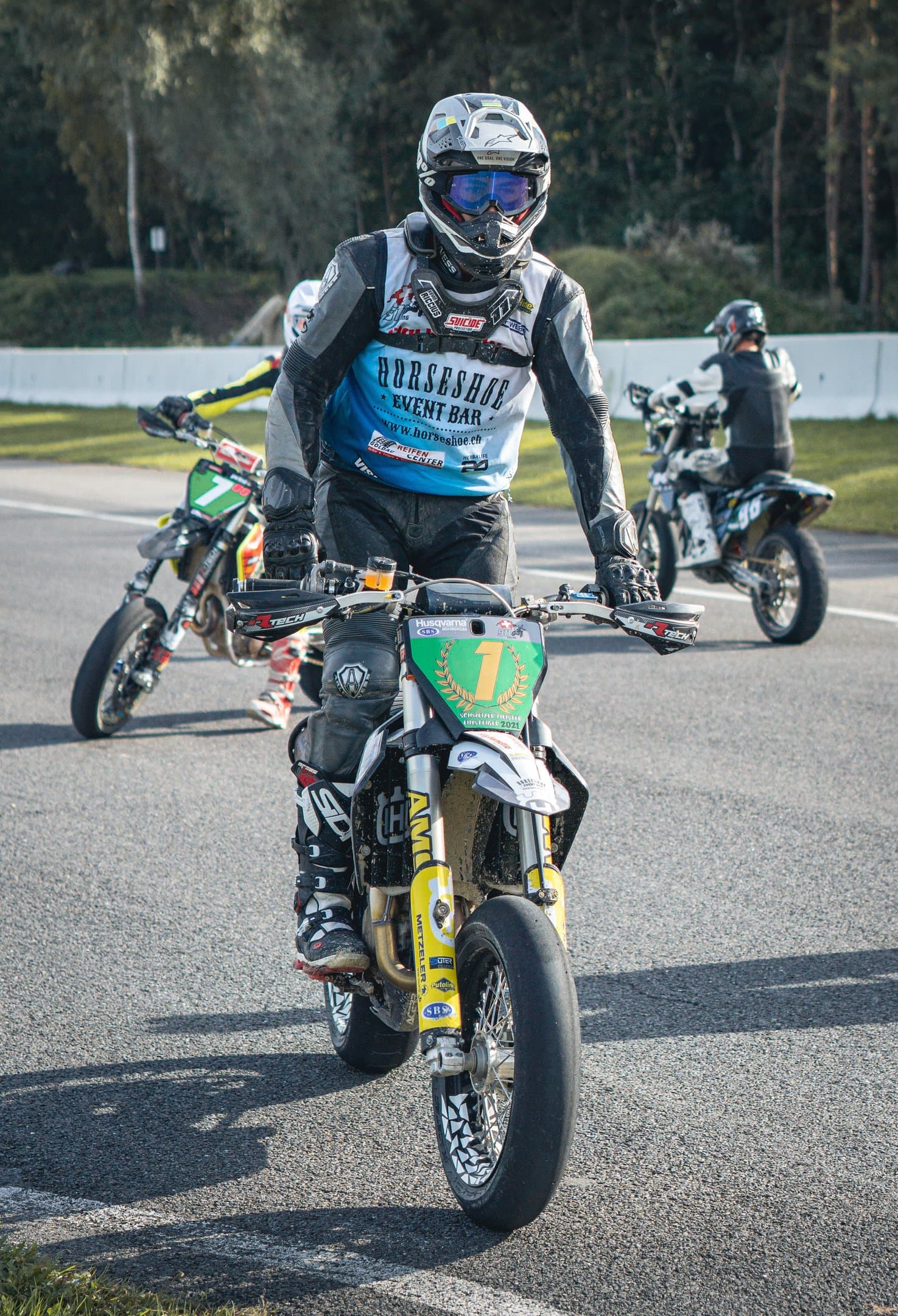 Supermoto-Fahrer beim Wheelie auf einer Rennstrecke