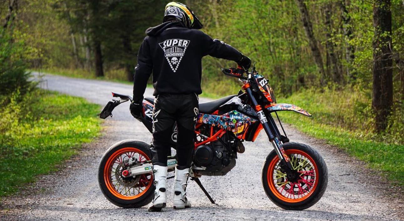 Supermoto-Fahrer mit Motorrad auf einer Waldstrasse